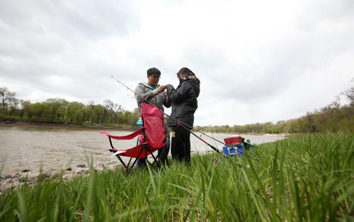 RUTH BONNEVILLE / WINNIPEG FREE PRESS   Steven Cheng shows his friend Chanel Lai how to set up her rod along the banks of the Red River in St. Vital Park Saturday on the first day fishing season in Manitoba.     May 14, , 2016