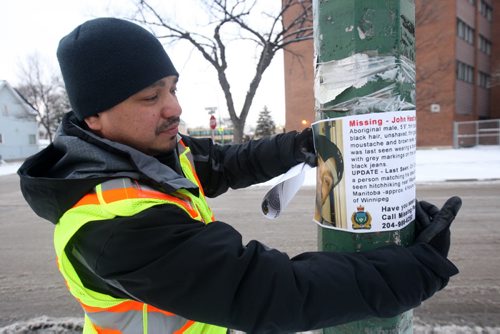 JOE BRYKSA / WINNIPEG FREE PRESS Bear Clan Patrol on patrol in Winnipegs North End  Clan member Harlin Bear tapes poster of missing person on lamp pole  in Winnipegs North End , March 17  , 2016.(see  Alex Paul story)