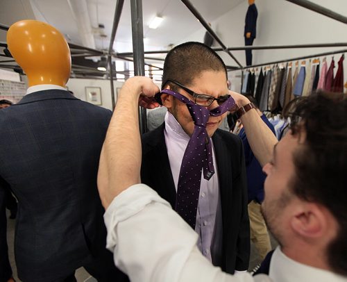 PHIL HOSSACK / WINNIPEG FREE PRESS -  SUITS FOR GRADS - Jimmy Boulanger squeezes his head into a new tie from Alex Ethan (right) of EPH Apparel putting the finishing touches on his new prom suit Monday. A couple of dozen graduating from Children of the Earth School are being given fitted suits for their Grad. See Alex Paul's story.  May 16, 2016