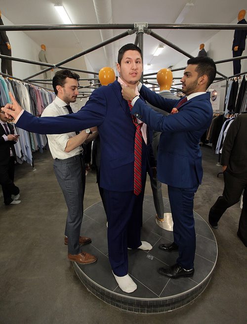 PHIL HOSSACK / WINNIPEG FREE PRESS -  SUITS FOR GRADS - Brendan Govereau checks out his reflection as Alex Ethan )left) and Sandeep Singh of EPH Apparel put the finishing touches on his new prom suit Monday. A couple of dozen graduating from Children of the Earth School are being given fitted suits for their Grad. See Alex Paul's story.  May 16, 2016