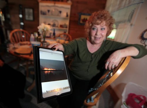 PHIL HOSSACK / WINNIPEG FREE PRESS -  Arlene Dorsette shows off a photo of the fire across the Caddy Lake bay that forced her and her husband Tom to evacuate. They're back in their full time residence as of noon Tuesday. See Alex Paul story.  May 16, 2016