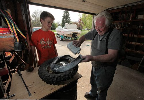 PHIL HOSSACK / WINNIPEG FREE PRESS - Willi Jantz, helps his grandson 14 yr old Lucas Kushnier repair a flat on his dirt bike. For a 49 feature on East and West St. Paul. Jantz moved here in 1971 when the smell from the oil refinery was so bad you could buy a house on an acre of land for $1,500, as he did. The refinery closed in few years later, and values shot up. Just the empty lots in town now sell for $250,000. Sill Redekopp's feature. May 18, 2016