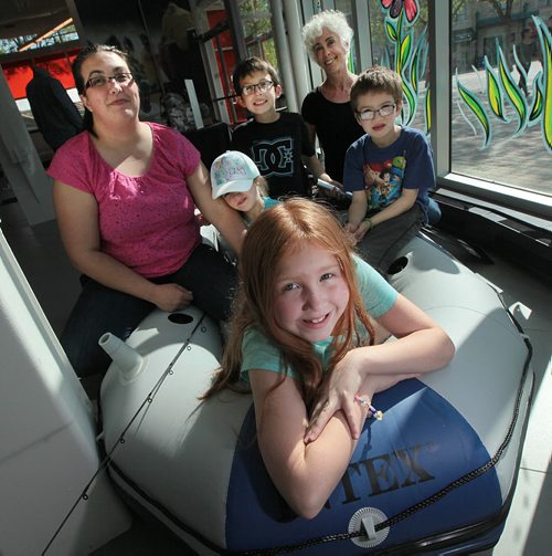 PHIL HOSSACK / WINNIPEG FREE PRESS - Camp quality - a week long summer camp for children with cancer and their siblings. Abigail Stewart sits in the bow of a boat at the Manitoba Travel building at the Forks, She's attended Camp Quality with her siblings Gabriel, (back in black) Zackery (right in Blue) and Savanna (beside mom in hat). Mom, Ashley (left) sits with the kids and Lois Weidman - longtime camp fundraiser sits in the stern. See Kevin Rollason's story. May 20, 2016