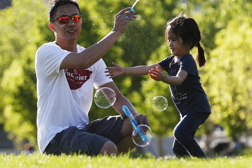 JOHN WOODS / WINNIPEG FREE PRESS Rudy Delacruz and his daughter Rylee chase bubbles at the Forks Monday, May 23, 2016.