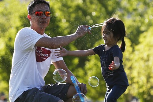 JOHN WOODS / WINNIPEG FREE PRESS Rudy Delacruz and his daughter Rylee chase bubbles at the Forks Monday, May 23, 2016.