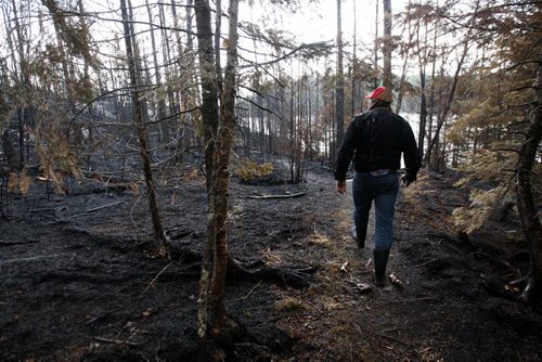 JOE BRYKSA / WINNIPEG FREE PRESS  Florence Lake cottager Ian Baragar surveys the burnt out shores of neighboring Nora Lake for the first time Tuesday , May 24 , 2016.(see Nick Martin  story)