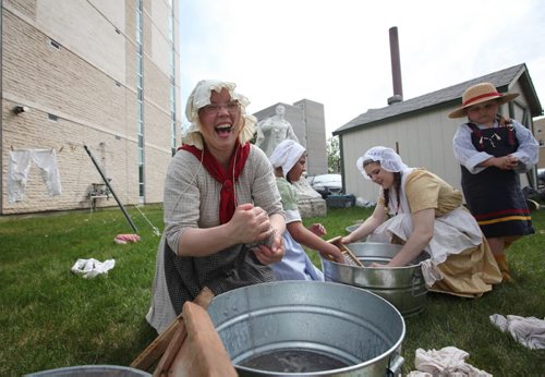 RUTH BONNEVILLE / WINNIPEG FREE PRESS  Genevieve Woods, a volunteer interpreter with The Manitoba Living History Society, demonstrates, along with other volunteer interpreters, to grades 5 & 6 social studies students from Immanuel Christian School how 1st settlers did their laundry outside the St. Boniface Museum Wednesday morning.
Standup photo 
 May 25, , 2016