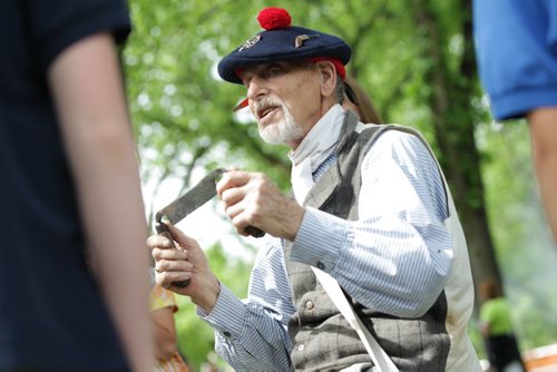 RUTH BONNEVILLE / WINNIPEG FREE PRESS  Ed Douglas, a volunteer interpreter with The Manitoba Living History Society, demonstrates to grades 5 & 6 social studies students from Immanuel Christian School how 1st settlers worked with wood outside the St. Boniface Museum Wednesday morning.  Standup Photo May 25, , 2016