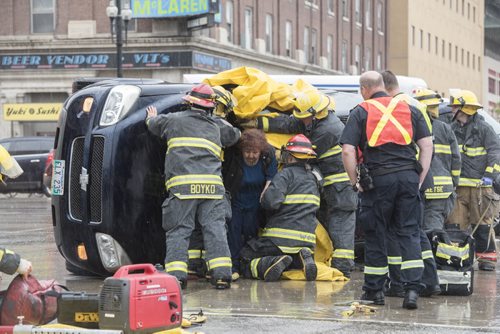 DAVID LIPNOWSKI / WINNIPEG FREE PRESS  Winnipeg Fire and Paramedics help occupants of a turned over van escape through the windshield at the corner of Rupert Ave and Main Street during rush hour traffic Wednesday May 25, 2016.