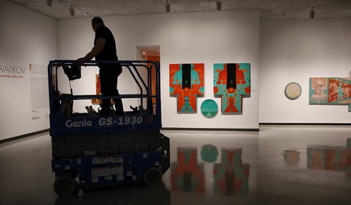 MIKE DEAL / WINNIPEG FREE PRESS  A WAG employee clears out the scissor lift before the opening of two exhibitions featuring 20th-century artist Marc Chagall and Esther Warkov one of Manitoba's most distinctive painters.  In the background is Warkov's Night Riders, 1971, oil on canvas.   160526 Thursday, May 26, 2016