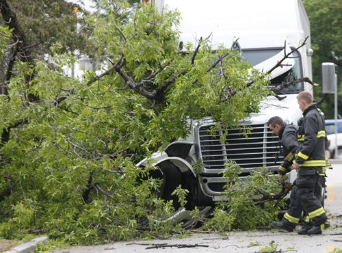 WAYNE GLOWACKI / WINNIPEG FREE PRESS    Winnipeg Fire Fighters at the scene of semi trailer that struck a tree by the corner of Main St. and Assiniboine Ave. Friday morning. Traffic from Main St. on to Assiniboine Ave. was blocked off for part of the morning . May 27   2016