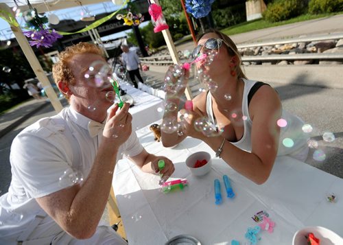 TREVOR HAGAN / WINNIPEG FREE PRESS Todd Chernomas and Carole Neudoft take a moment to blow some bubbles while preparing their table for Table for 1200, along Waterfront Drive, Saturday, May 28, 2016.