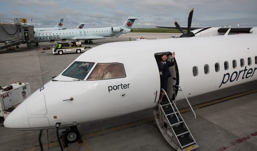 MIKE DEAL / WINNIPEG FREE PRESS Flight attendant Patricia Marzec waves as the Porter Airline flight for Toronto leaves Winnipeg. Marzec has been with Porter since it started in 2006. 160529 - Sunday, May 29, 2016