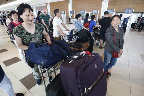 JOHN WOODS / WINNIPEG FREE PRESS Jian Wyatt (L) and other Air China passengers wait to check-in to board a plane out of Winnipeg Sunday, June 5, 2016. Passengers from an Air China had to make an unscheduled stop in Winnipeg when their flight made an emergency landing last night.