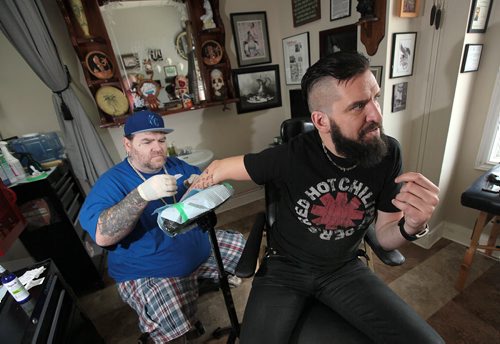 PHIL HOSSACK / WINNIPEG FREE PRESS - SUNSHINE FUND - Robb Nash, who performs at high schools all over the country as part of the Robb Nash Project giving hope to teens who are struggling and contemplating suicide. He's getting the names of a bunch of kids who either ripped up their suicide notes or surrendered them to him tattooed on his arm.  Tattoo Artist Phil MacLellan applies his ink. Phil would prefer his real name NOT be used and rather be called "Fat Phil", seriously.......See story.  June 9, 2016
