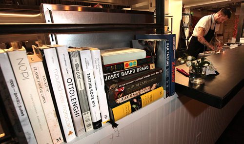 PHIL HOSSACK / WINNIPEG FREE PRESS - A library of Cooking reading sits accessible to diners as Chef and owner Adam Donnelly preps delights at the eccentrically decorated Clementine Cafe.See Review.  June 13, 2016