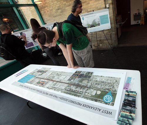 PHIL HOSSACK / WINNIPEG FREE PRESS -  Cyclist Evan Proulx (centre in green) gets a close lookat maps  of proposed downtown bike lanes Thursday at an open house held at the Forks to get input from Winnipeggers. See Ashley Prest story. - See story. June 23, 2016