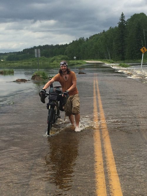 JOE BRYKSA / WINNIPEG FREE PRESS Peter Auzinger of Austria, who is cycling across Canada, walks through flood water on Highway 44 near the Whiteshell. Saturday, June 25, 2016
