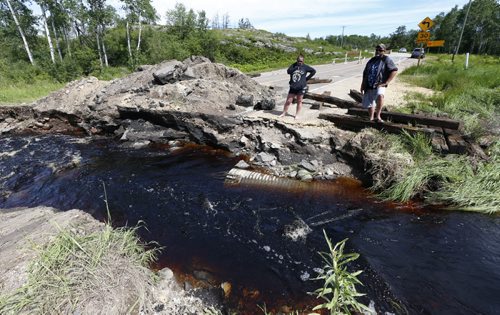 WAYNE GLOWACKI / WINNIPEG FREE PRESS  Ken Hunt and Krista Cornell on Highway 307 near Highway 44 where a track hoe was used Sunday to remove the culvert and a section of the road to release water buildup.  Bill Redekop Story June 27  2016