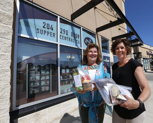 WAYNE GLOWACKI / WINNIPEG FREE PRESS      At right, Lori Vassart holds Bruschetta Pasta and Hollow Mushroom Stuffed Burgers meals beside Crystal Anderson with Nacho Packs in front of their Supper Central in the Kenaston Common. Murray McNeill  Story June 28  2016