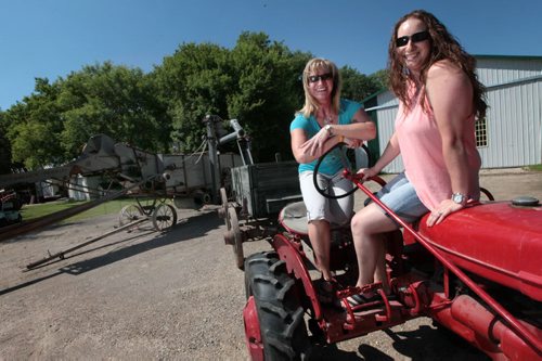 PHIL HOSSACK / WINNIPEG FREE PRESS - Barry Klym's daughters Angioe (left) and Erin pose on a McCormick Farmall tractor Tuesday afternoon.  Barry's taking the machines and his daughters to the Austin Thresherman's Reunion where the family passion for antique farm equipment will be on display. - See Bill Redekop story. June 28, 2016