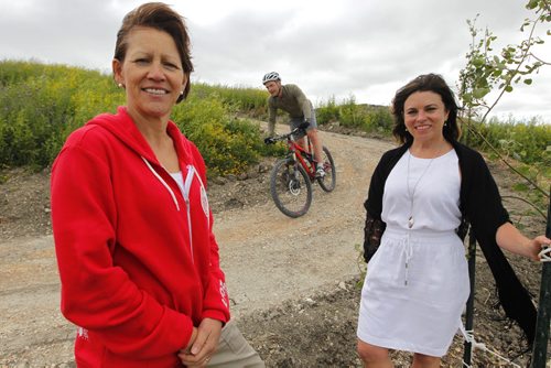 BORIS MINKEVICH / WINNIPEG FREE PRESS (L-R) Canada Games rep Janet McMahon and Twila Cruickshank, executive director, Manitoba Cycling Association pose on new site of biking venue near FortWhyte Alive, 1961 McCreary Rd.  Community Places program investments in recreational and cultural facilities across the province including a new venue for the 2017 Canada Games. Cyclist in behind is Russell Dyck. June 30, 2016