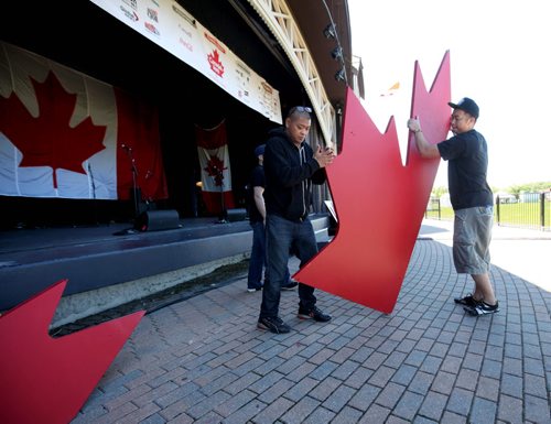 RUTH BONNEVILLE / WINNIPEG FREE PRESS  Crew members with Canad Inns move a huge red maple leaf in front of the Lyric Stage as the finishing touches are put into place for Canada Day Celebrations at Assiniboine Park Thursday afternoon. Standup photo  June 30 / 2016