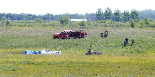 Ruth Bonneville / Winnipeg Free Press   Rescue crews make their way back up the hill after covering the cockpit of a small plane with a tarp after it  crashed just north of Number one highway, east of the floodway Friday morning.  It took off from Lyncrest Airport earlier in the day with two people on board.  Both are presumed to have died in the crash.  No other details are available at this time.      July 01/2016