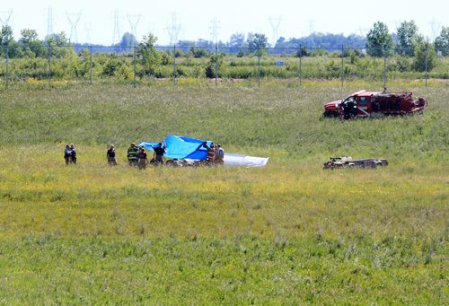 Ruth Bonneville / Winnipeg Free Press   Rescue crews cover the cockpit of a small plane that crashed just north of Number one highway, east of the floodway Friday morning.  It took off from Lyncrest Airport earlier in the day with two people on board.  Both are presumed to have died in the crash.  No other details are available at this time.      July 01/2016