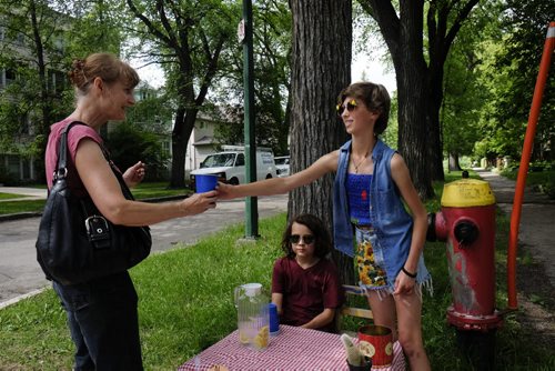 ZACHARY PRONG /  WINNIPEG FREE PRESS  Nora, right, and Kiko sell Sandy Sawatzky lemonade at their stand in Woseley. The cousins are trying to raise money for Folk Fest. July 4, 2016.