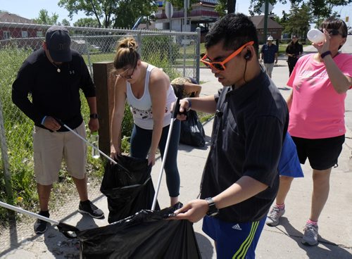 ZACHARY PRONG / WINNIPEG FREE PRESS  Participants in the Village Walk, a community event that takes place every Monday throughout the summer, pick up garbage as they stroll through Winnipeg's North End. The Village Walk was founded by Jade Harper in the hopes of promoting fitness, building community and teaching people about the city's historic North End. From right to left, Pamela Leost, Chris Clacio, Jade Harper and Will Smith.