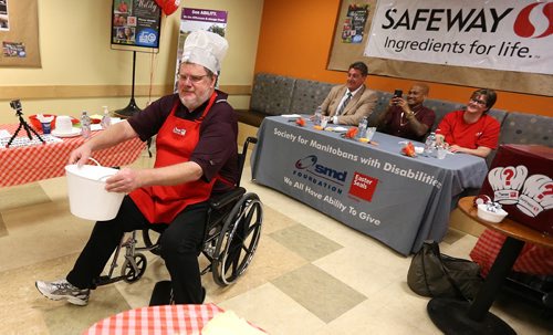 JASON HALSTEAD / WINNIPEG FREE PRESS  Winnipeg Free Press columnist Doug Speirs rolls past the judges at the Society for Manitobans with Disabilities (SMD)/Easter Seals Manitoba Celebrity Cook-Off for Kids competition during the 2016 Safeway Campaign Launch at Madison Square Safeway on June 29, 2016. Local media celebrities navigated a competition kitchen in wheelchairs to prepare camp-themed dishes for a panel of three judges. (See Social Page)