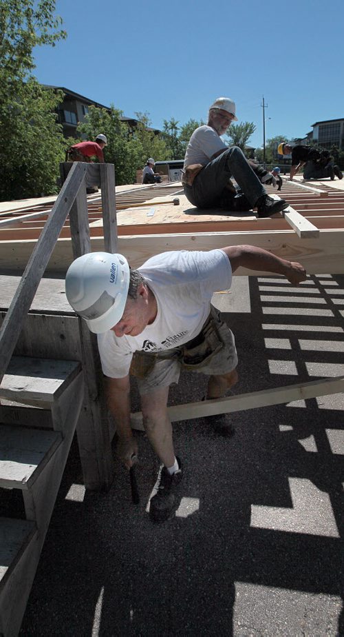 PHIL HOSSACK / WINNIPEG FREE PRESS - Anthony Schick scrambles out from underneat Don Petkau Tuesday afternoon as the pair hammer floor braces into place at the latest Habitat for Humanity home. The St Vital interfaith project is building a "Ready To Move" home on the parking lot of the Evangelical Mennonite Church on St Mary's Road. See release/story? July 5, 2016