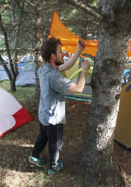JOE BRYKSA / WINNIPEG FREE PRESS Campers arrive at their campsites to kick off the 2016 Winnipeg Folk Fest at Birds Hill Park Wednesday morning- Ben Rissin sets up a tarp at the campground. Festival music starts tomorrow and will run until July 10-July 06, 2016 -(Standup Photo)