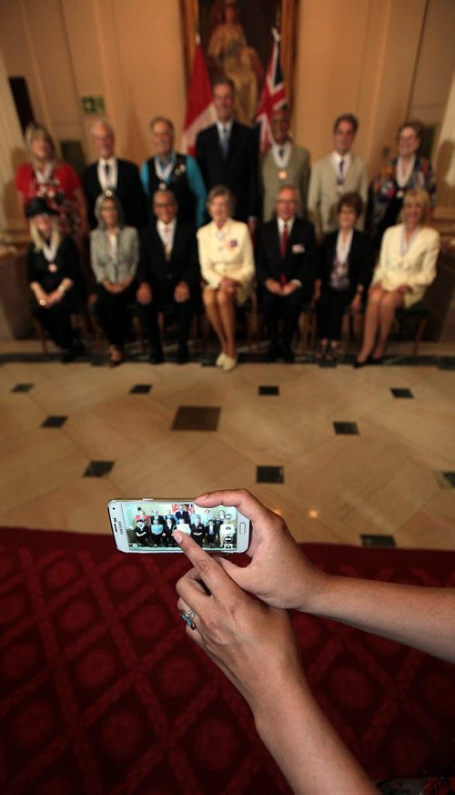 PHIL HOSSACK / WINNIPEG FREE PRESS - An Order of Manitoba Fan reaches around in front of the "official" camera's to nab a group portrait of the recipients with the Lt Govenor and Premier.. See story. July 7, 2016