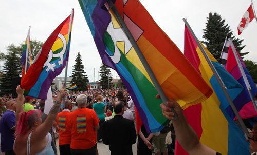 RUTH BONNEVILLE / WINNIPEG FREE PRESS  Flag bearers hold their rainbow flags high on the steps of city Hall in Steinbach as thousands gather to listen to speeches and celebrate Steinbach's 1st ever Pride march Saturday.    July 09, 2016