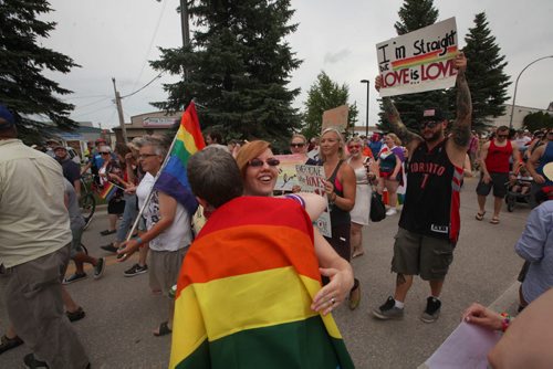 RUTH BONNEVILLE / WINNIPEG FREE PRESS  Michelle McHale (right, red dress)  and her partner Karen Phillips (rainbow flag over back) celebrate with friends and supporters walking in the march to  city hall to celebrate Steinbach's 1st ever Pride march Saturday.   July 09, 2016