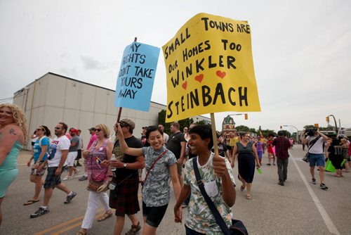 RUTH BONNEVILLE / WINNIPEG FREE PRESS  Adrienne Yeung  (right)  and her partner Tharuna Abbr hold signs as the walk with thousands of others across Main Street to the steps of City Hall to celebrate Steinbach's 1st ever Pride march Saturday.    July 09, 2016