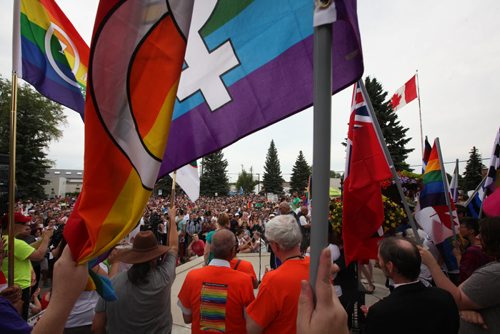 RUTH BONNEVILLE / WINNIPEG FREE PRESS  Flag bearers hold their rainbow flags, Manitoban flag and Canadian flag high on the steps of city Hall in Steinbach as thousands gather to listen to speeches and celebrate Steinbach's 1st ever Pride march Saturday.    July 09, 2016