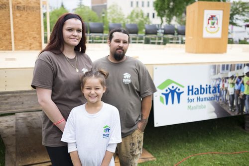 ZACHARY PRONG / WINNIPEG FREE PRESS  Sasha Ward, Kyle Warren and their daughter Hailey Warren, 7, in front of what will soon be their new home built by Habitat for Humanity. The home will be built over two weeks with volunteers from the University of Winnipeg, Canadian Institute of Plumbing and Heating, Investors Group and Sustainable Forestry Initiative. July 11, 2016.