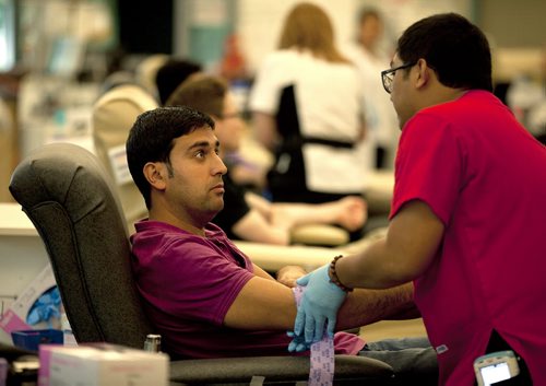PHIL HOSSACK / WINNIPEG FREE PRESS - Karwan Kahil listens intently as Phlebotomist, Dan Caballero gives instruction after Kahil donated Blood for his first time in Canada. His first donation was in Syria to help his father through open heart surgery. Karwan  and other members of the Syrian Community took time to volunteer blood donations at the Canadian Blood Services Monday evning. See Carol Sanders story. July 11, 2016