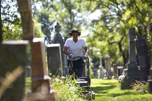 RUTH BONNEVILLE / WINNIPEG FREE PRESS  The Cathedral Church of Saint John grounds keeper, Dennis Bealieu, works his way around the headstones and uneven ground to mow the lawn in the historic cemetery Friday.    July 15, 2016