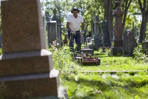 RUTH BONNEVILLE / WINNIPEG FREE PRESS  The Cathedral Church of Saint John grounds keeper, Dennis Bealieu, works his way around the headstones and uneven ground to mow the lawn in the historic cemetery Friday.    July 15, 2016