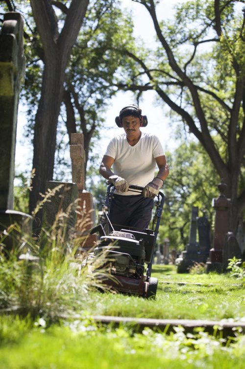 RUTH BONNEVILLE / WINNIPEG FREE PRESS  The Cathedral Church of Saint John grounds keeper, Dennis Bealieu, works his way around the headstones and uneven ground to mow the lawn in the historic cemetery Friday.    July 15, 2016