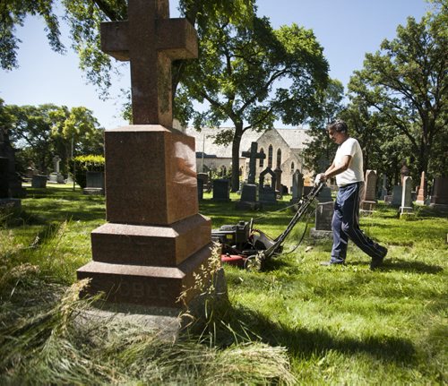 RUTH BONNEVILLE / WINNIPEG FREE PRESS  The Cathedral Church of Saint John grounds keeper, Dennis Bealieu, works his way around the headstones and uneven ground to mow the lawn in the historic cemetery Friday.    July 15, 2016