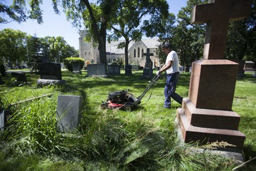 RUTH BONNEVILLE / WINNIPEG FREE PRESS  The Cathedral Church of Saint John grounds keeper, Dennis Bealieu, works his way around the headstones and uneven ground to mow the lawn in the historic cemetery Friday.    July 15, 2016