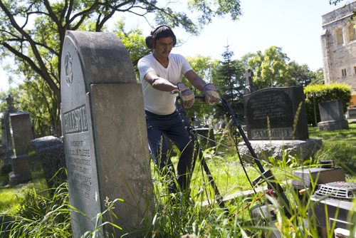 RUTH BONNEVILLE / WINNIPEG FREE PRESS  The Cathedral Church of Saint John grounds keeper, Dennis Bealieu, works his way around the headstones and uneven ground to mow the lawn in the historic cemetery Friday.    July 15, 2016