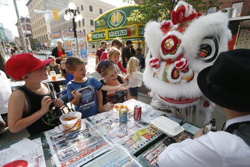 JOHN WOODS / WINNIPEG FREE PRESS Noah, Cole and their mother Shawna Christie say say hi to the Causin a Commotion chinese lion as they have some snacks at the Winnipeg Fringe Festival Sunday, July 17, 2016.