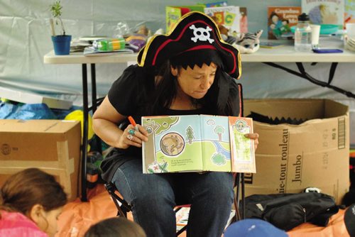 Canstar Community News A volunteer reads for kids at the 2015 Picnic in The Park hostes by the North End Community Resource Centre. (Supplie photo/The Times)