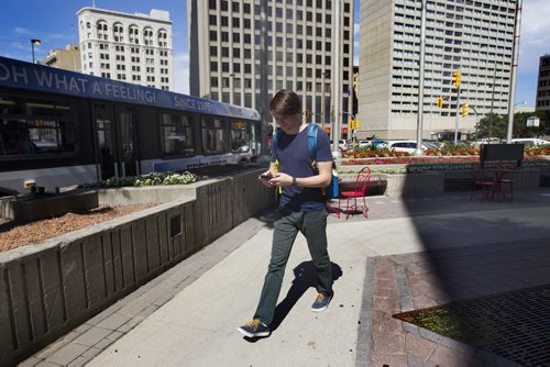 RUTH BONNEVILLE / WINNIPEG FREE PRESS  Photos of the corner of Portage Ave. and Main Street for story on opening the intersection up for pedestrian traffic. Connor Livingston walks on the south west corner of the intersection Wednesday rushing to catch his bus.      July 20, 2016